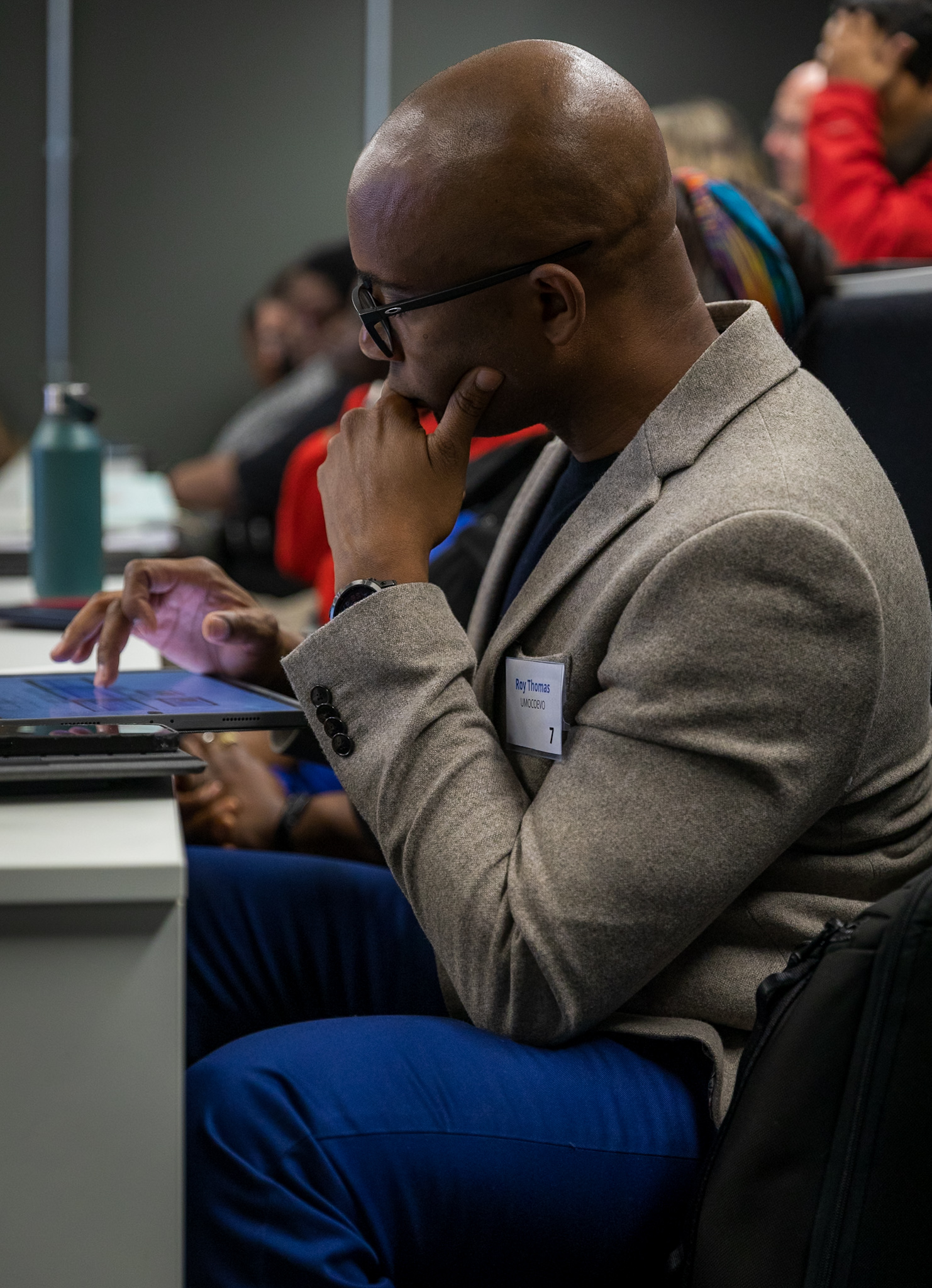 Roy Thomas engaged with a tablet in a professional setting, symbolizing focus and digital interaction.